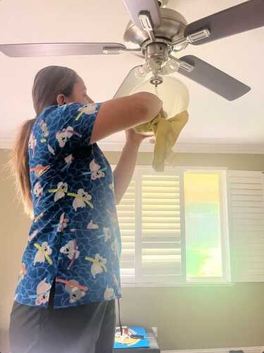 Alma Lizzeth Osorio Castro cleaning a ceiling fan professionally